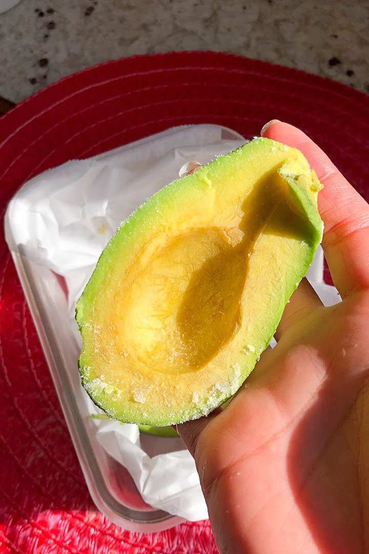 Frozen Avocado half held in hand.