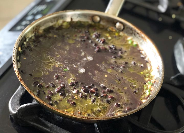 Black beans and all sauteed ingredients simmering in pan on stove top.