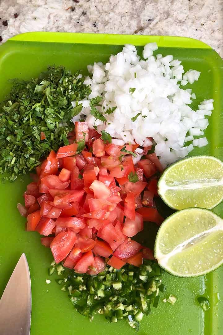 ingredients to make authentic pico de gallo recipe diced on a chopping board.