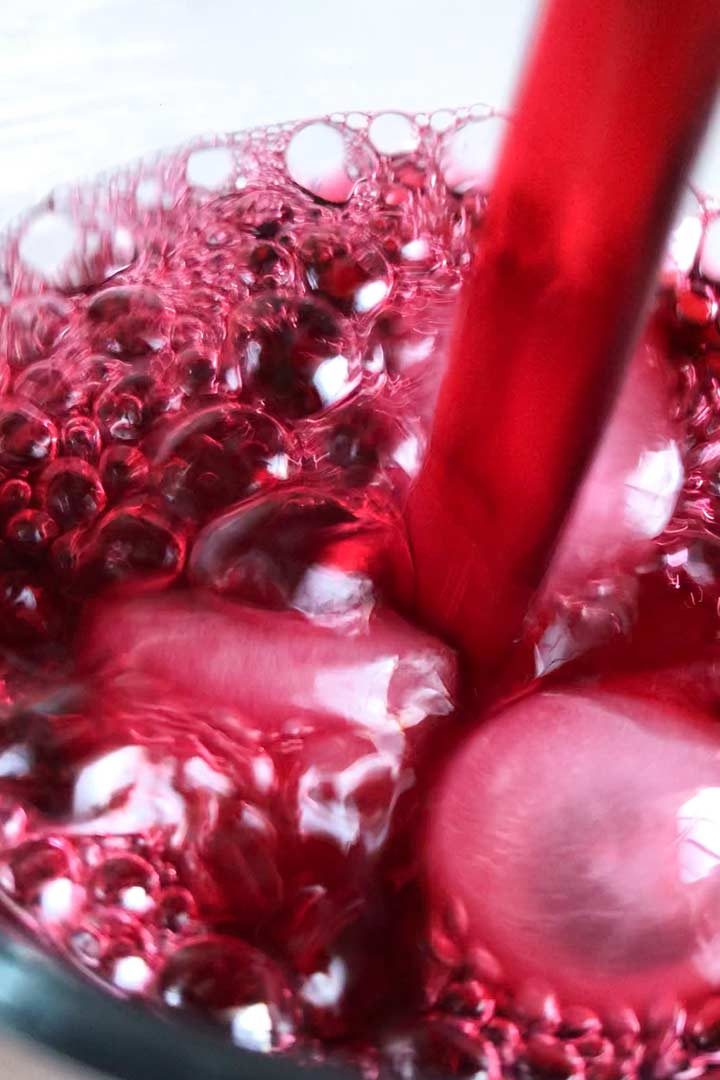 Up close pouring ice cold Agua de Jamaica Agua Fresca drink.