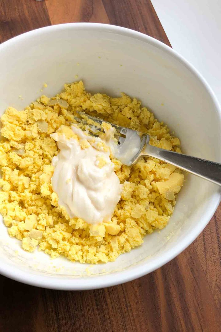How to make egg salad step 2, adding mayonnaise to broken up yolks.