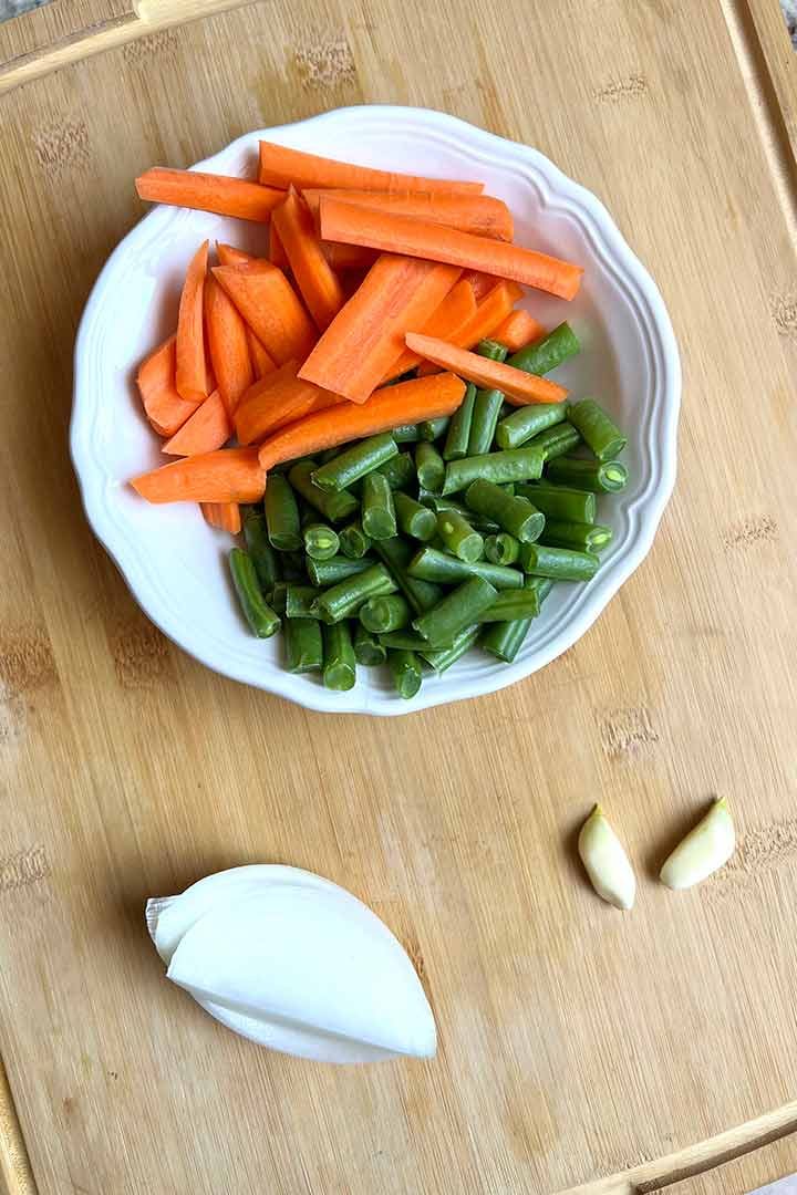 Fresh diced carrots, green beans, white onion piece and two garlic cloves.