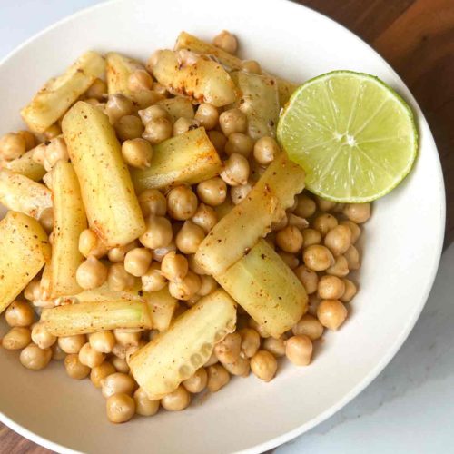 Garbanzo Bean Snack in a bowl with halved lime on white surface.