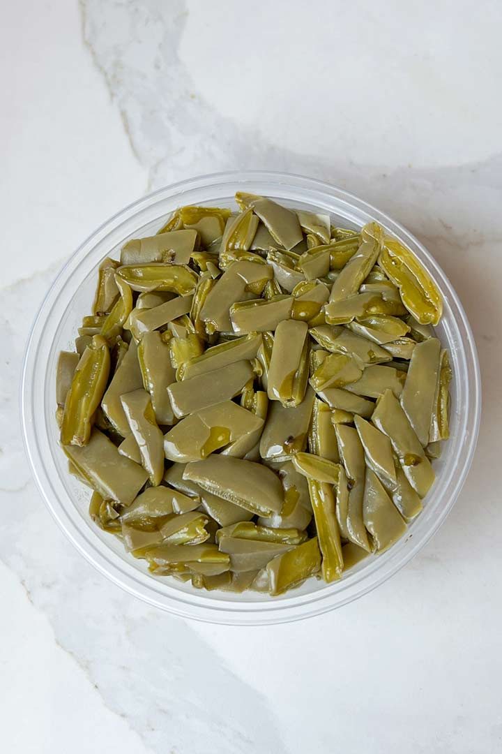 Ingredient, cold packaged nopales in a round container on white surface.