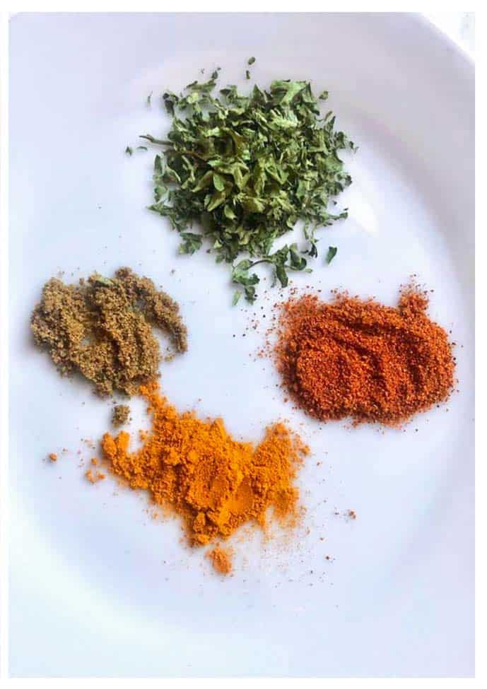 parsley flakes, ground paprika, turmeric and cumin on kitchen surface.