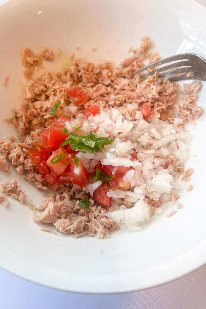 Process Step to mix the fresh tuna a la mexicana with fresh diced onion, tomato, and spicy serrano pepper.
