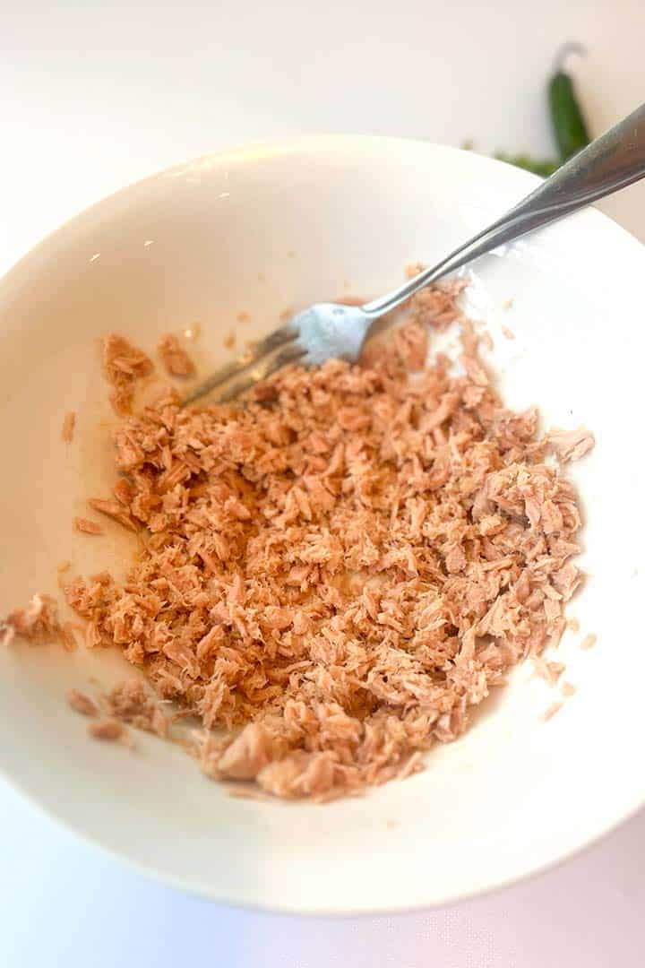 Process step to flake tuna up in a bowl with fork.