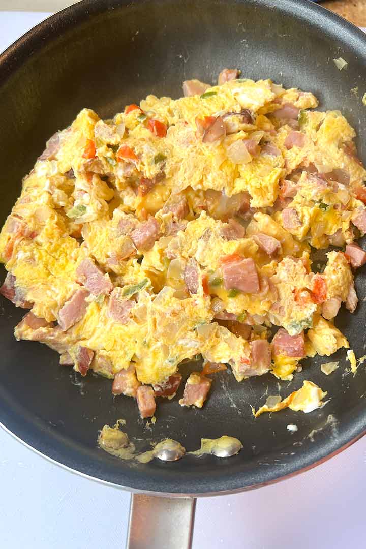 Fresh fluffy cooked leftover ham and eggs scramble recipe in a nonstick pan.