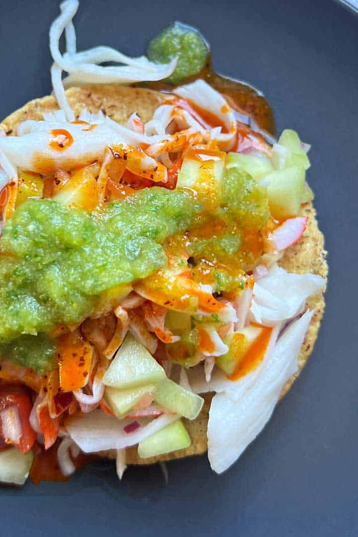 Salsa de Cacahuate poured over tostada de ceviche jaiba and fake guacamole.