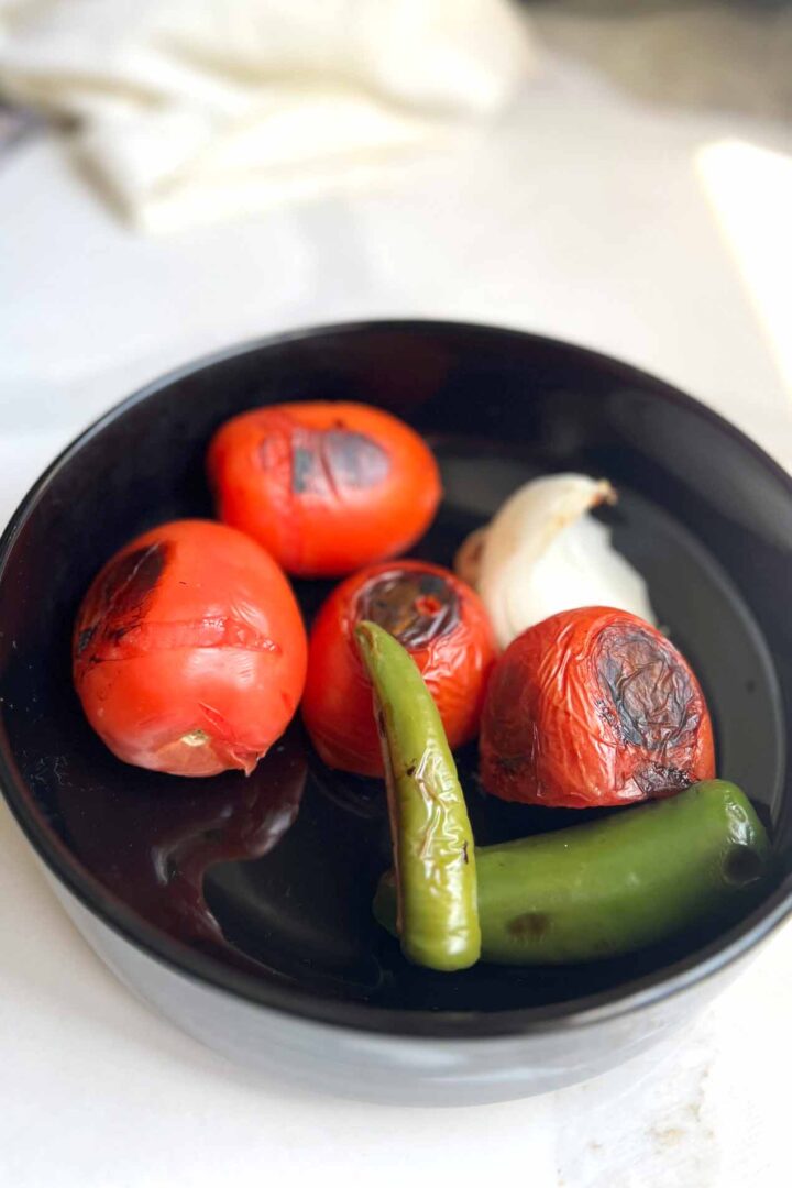 grilled salsa ingredients cooling down in a bowl.