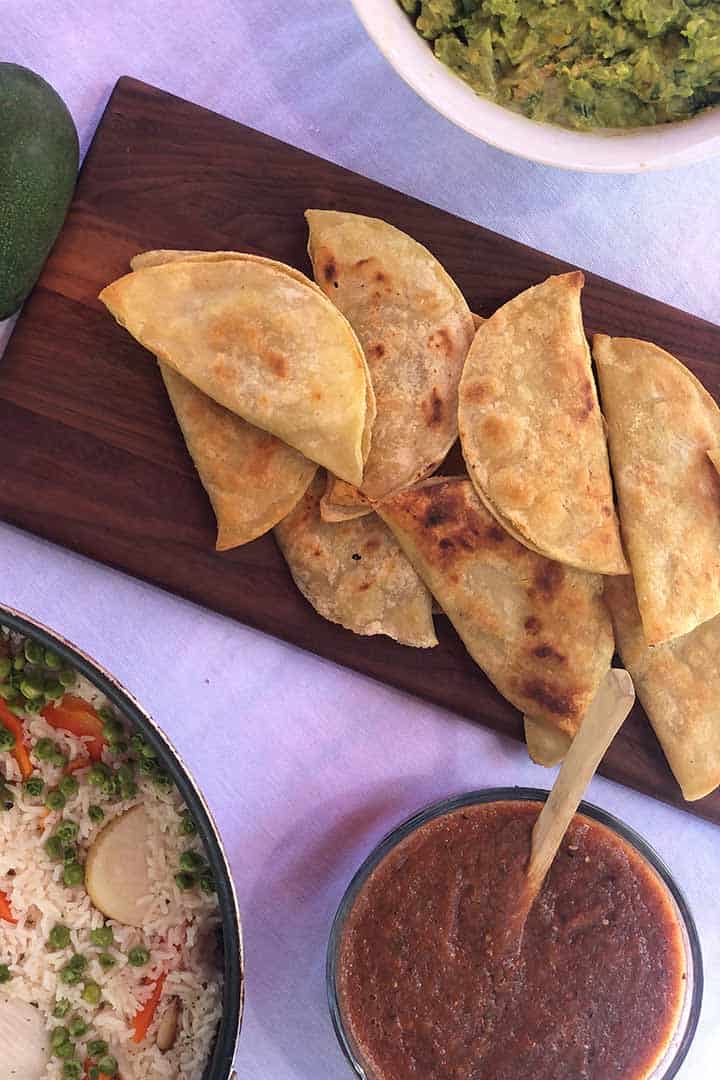 Crispy Mexican Potato Tacos recipe served with gucamole, salsa and rice on a custom dark wood platter.