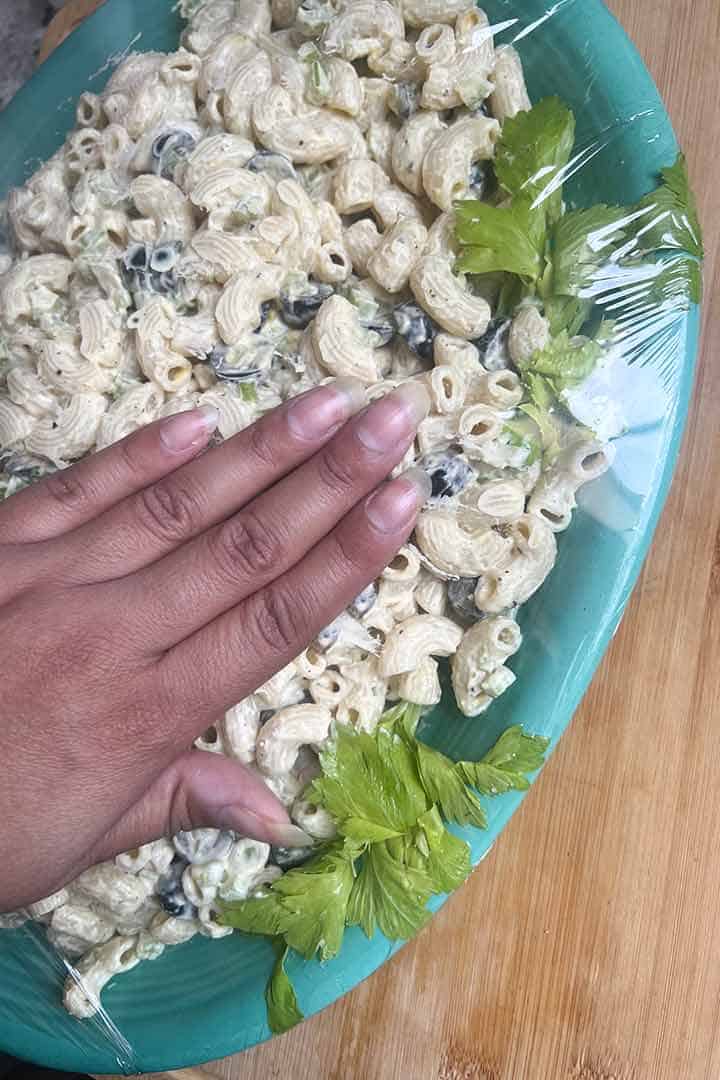 hand-firmly-wrapping-party-platter-of-Classic-Macaroni-salad