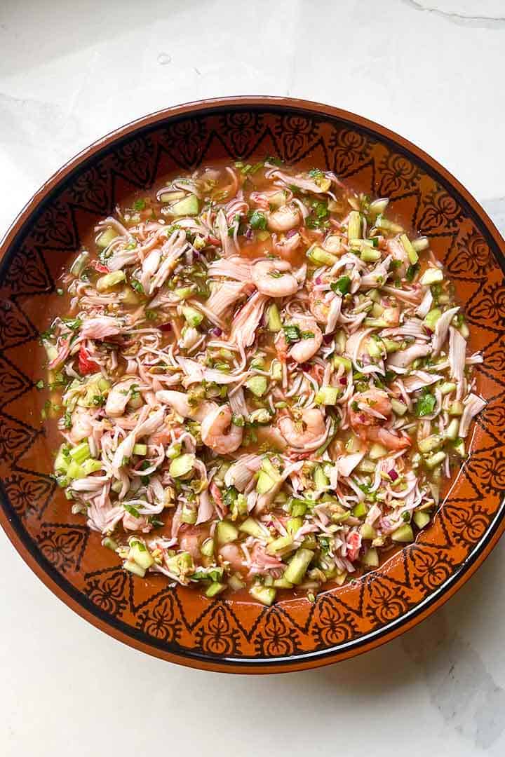 mixed Seafood Coctel in large round bowl on white quartz kitchen surface.