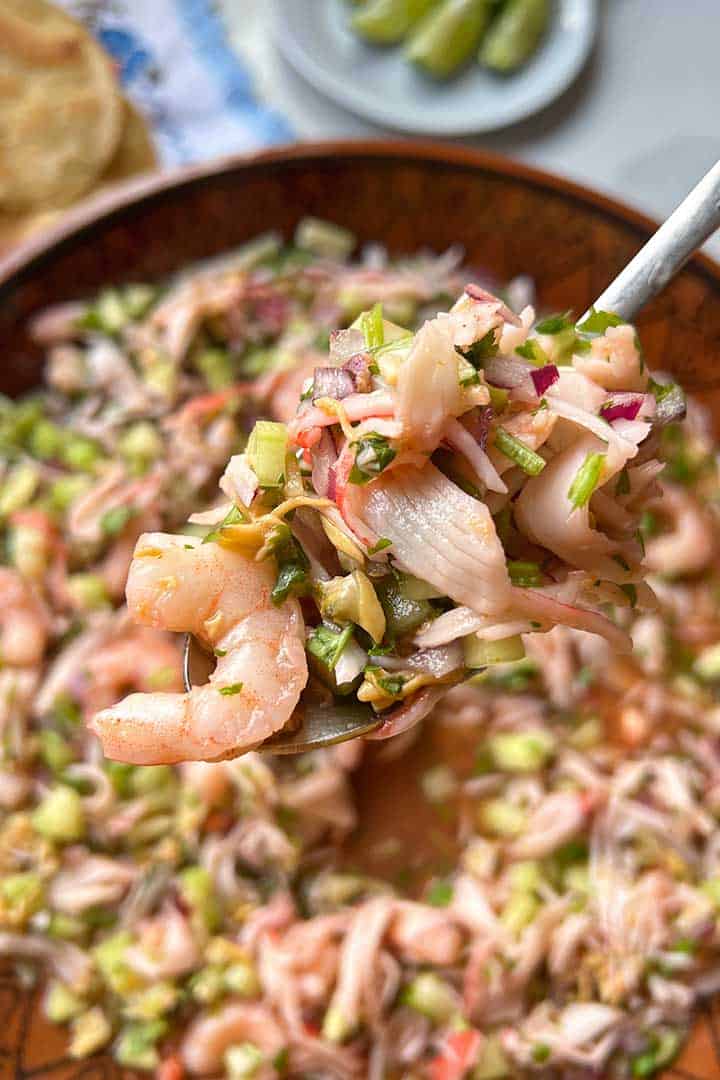 Spoonful of Seafood Imitation crab ceviche recipe held up with bowl of jaiba in background.