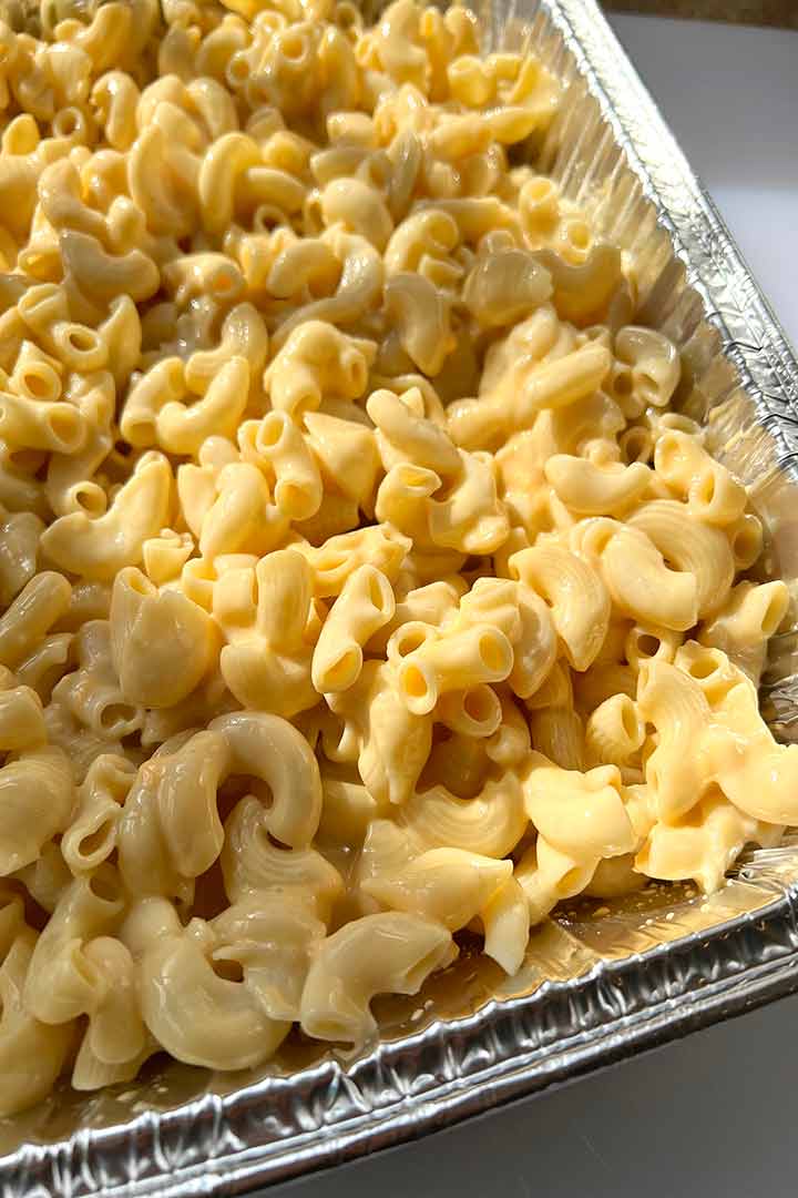 Process step once cooked macaroni and cheese sauce are mixed together in aluminum tray.