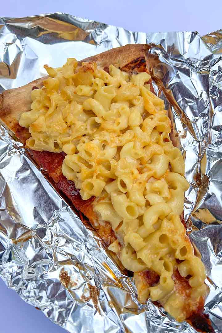slice of pizza baked with Macaroni and Cheese top. pizza with macaroni and cheese.