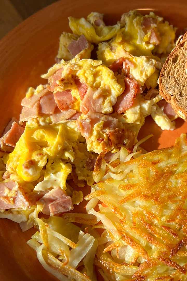 salty ham and eggs breakfast next to hash brown.