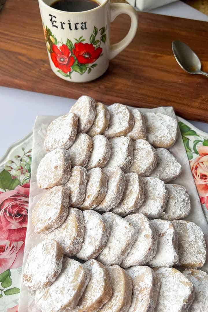 Large plate of Mexican Wedding Cookies Recipe on a plate with a personalised cup of Cafe de Olla above it.