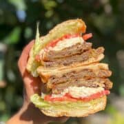 Best Milanesa Steak torta halved and held up in hand.