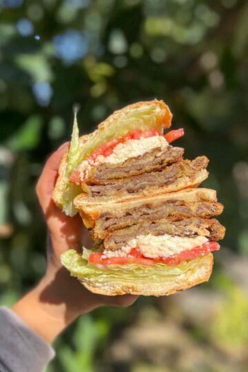 Best Milanesa Steak torta halved and held up in hand.