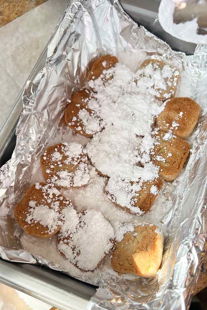 Coating the cookies with confectioners sugar known as powdered sugar.
