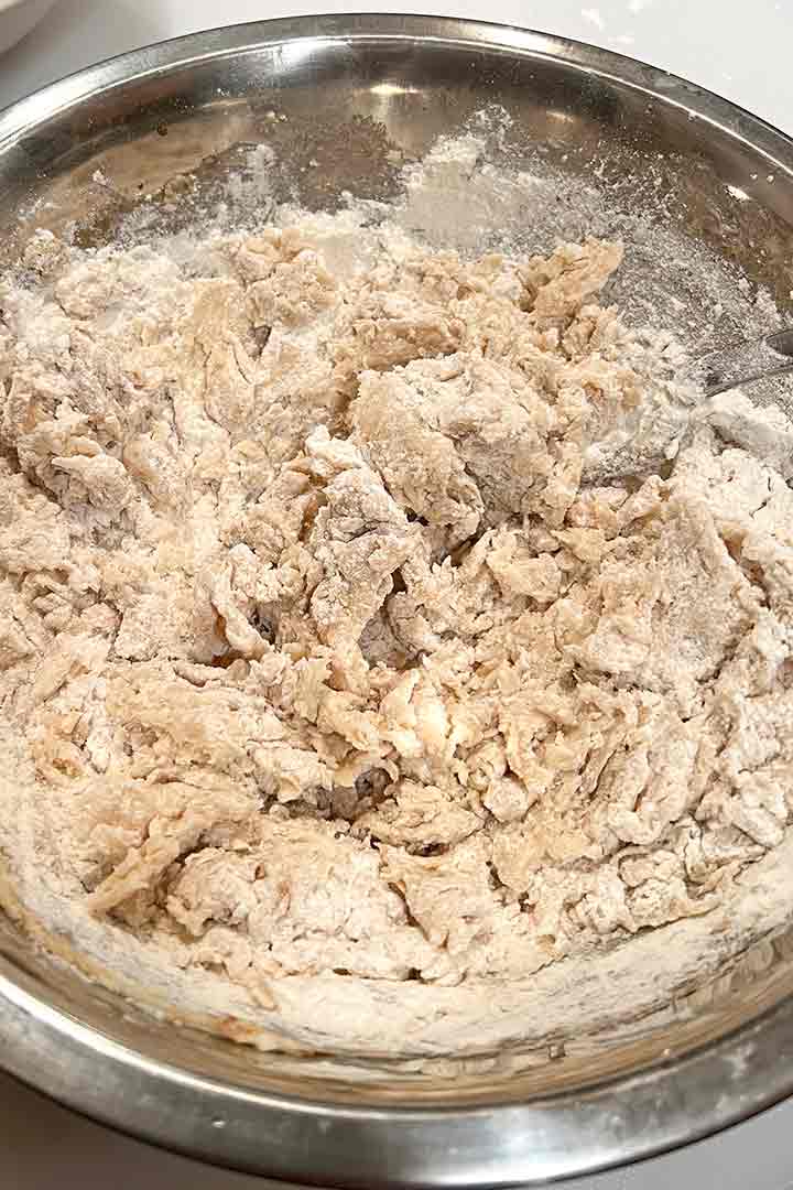 Mixing the first half of flour into the butter mixture in a round mixing bowl.
