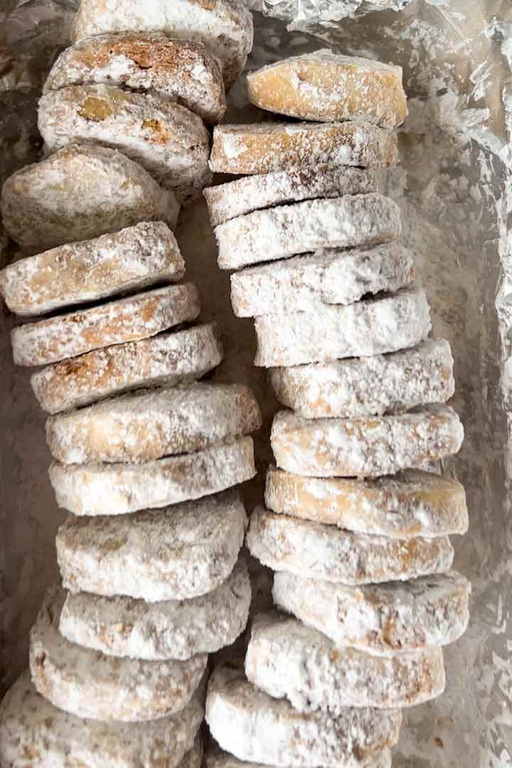 Two rows of Mexican Wedding Cookies lined up in a cookie tray.