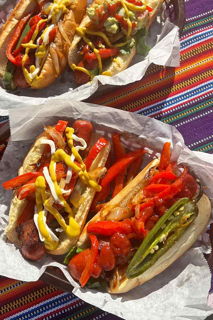 Four Mexican hot dogs topped with various ingredients and sauces