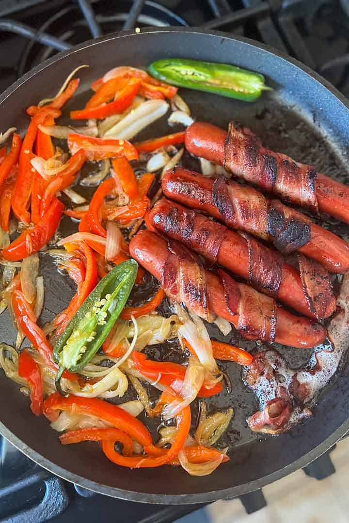 Mexican hot dogs and toppings being cooked on a grill