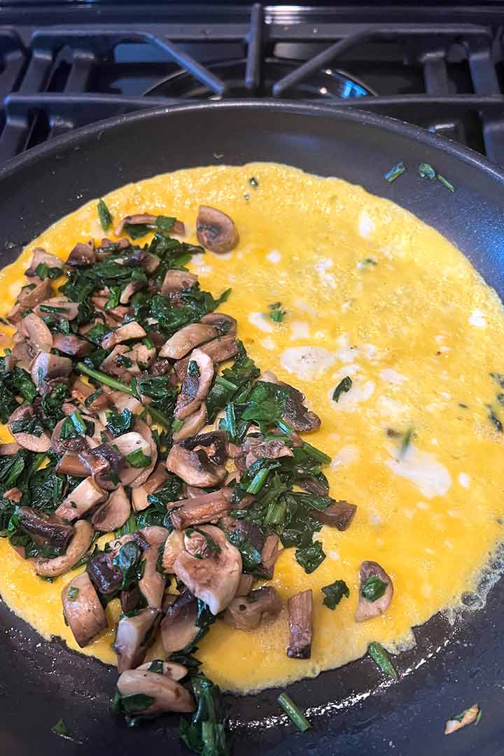 Filling of half of the omelette with vegetable mix.