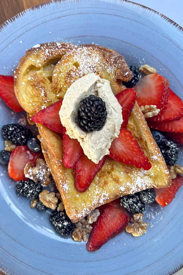 French Toast recipe with Fresh berry topping and whip cream on a blue plate.