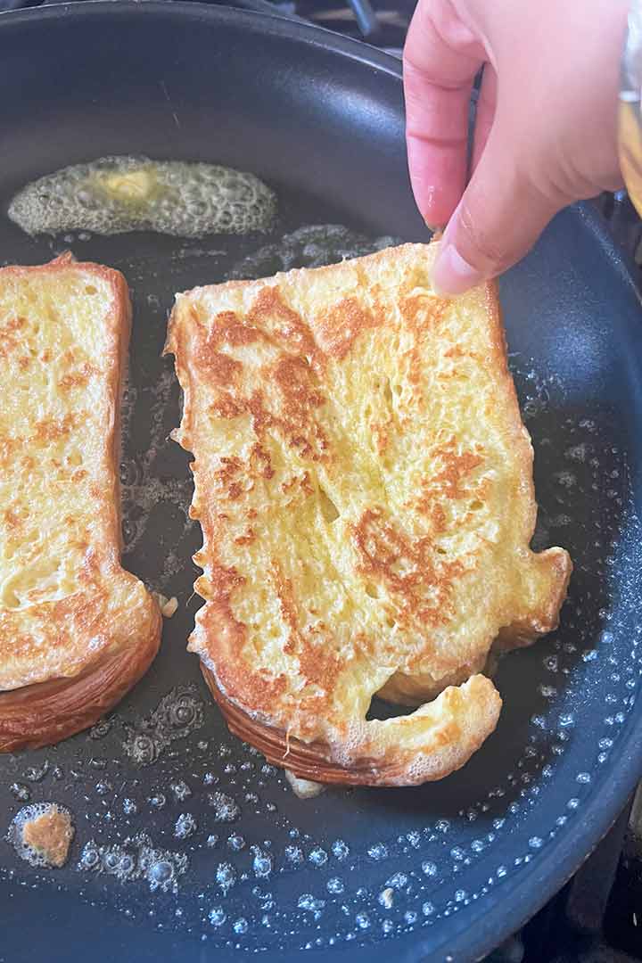 hand flipping the french toast in the hot pan over butter.