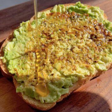 fresh mashed Avocado Toast with chili flakes and wildflower honey drizzle.
